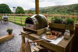 een grill met een pizza op een houten tafel bij Elephant View Shepherds Hut in Caernarfon
