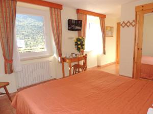 a bedroom with a bed and a window and a table at Albergo Eden in Passo del Tonale +11 photos