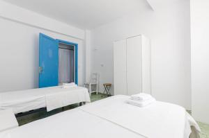 Duas camas num quarto branco com uma porta azul em La Marina CH em Cala Figuera