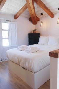 Schlafzimmer mit einem großen weißen Bett und Holzdecken in der Unterkunft Qué bueno que viniste. Edificio singular in Plasencia