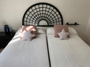 a bed with white sheets and two pillows on it at Wonderful Apartment on the Beach in Son Parc