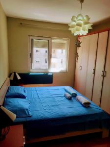 een slaapkamer met een bed met blauwe lakens en een raam bij Myslym Shyri lovely top apartment in Tirana