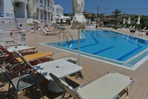 a pool at a hotel with chairs and a table at Kokalakis Hotel in Kefalos