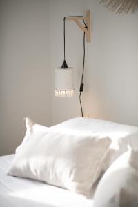 a bed with white sheets and a lamp on it at Phos Boutique Apartments in Aegiali