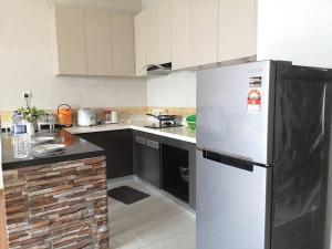 eine Küche mit einem Kühlschrank und schwarzen und weißen Schränken in der Unterkunft Country Garden Bay Point Homestay By Easyhomestay in Johor Bahru