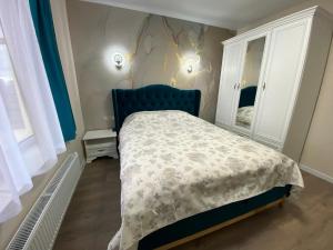 una camera da letto con letto con testiera blu e specchio di Нові апартаменти на Роксолани16 a Truskavec'