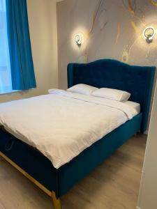 ein blaues Bett mit weißer Bettwäsche und Kissen darauf in der Unterkunft Нові апартаменти на Роксолани16 in Truskawez