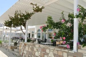 a patio with tables and chairs and pink flowers at Kokalakis Hotel in Kefalos