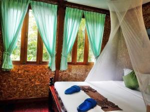 Schlafzimmer mit einem Bett mit blauer Bettwäsche und Fenstern in der Unterkunft Tree Tops River Huts in Khao Sok