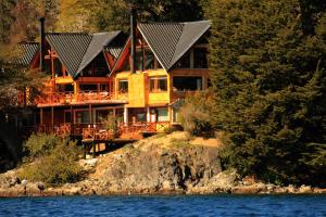 a large house with solar panels on the side of the water at Posada La Escondida in Villa Pehuenia