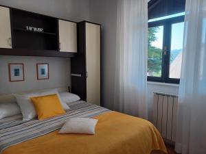 1 dormitorio con 1 cama con manta amarilla y ventana en Apartments Marion Klenovica, en Klenovica