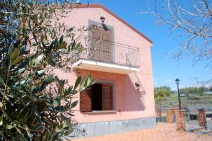 uma casa cor-de-rosa com uma varanda e uma árvore em Casa Farlazzo em Zafferana Etnea