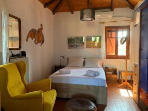 a bedroom with a bed and a yellow chair at Mavilia Traditional Guesthouse in Ligourio