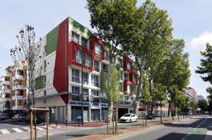 um edifício vermelho e branco numa rua da cidade em Résidence Néméa Tolosa em Toulouse