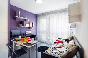 Habitación pequeña con mesa y pared púrpura. en Résidence Néméa Tolosa en Toulouse