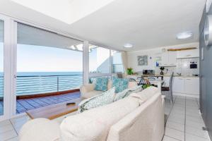 a living room with a couch and a kitchen at Ocean Blue at Chakas Cove, Beachfront Apartment in Ballito