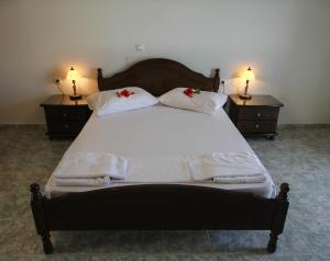 a large bed with white sheets and red flowers on it at Hotel Villa Basil in Tsilivi