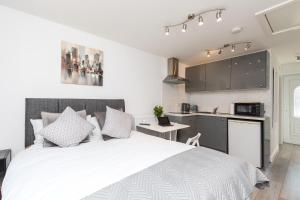 a bedroom with a white bed and a kitchen at Findon- Stylish Suite 10mins close to Airport in Crawley