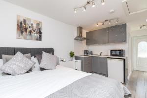 a bedroom with a white bed and a kitchen at Findon- Stylish Suite 10mins close to Airport in Crawley +10 photos