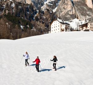 3 persone che praticano sci di fondo su una montagna innevata di Hotel Miramonti Corvara a Corvara in Badia