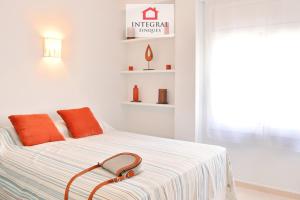 a white bedroom with a bed with orange pillows at Blue Wave Apartment in Calonge