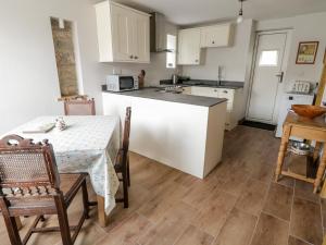 cocina con armarios blancos, mesa y sillas en Box Tree Cottage, en Keighley