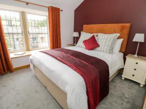 a bedroom with a large bed and two windows at Box Tree Cottage in Keighley