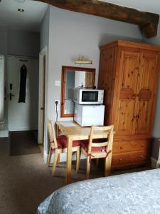 a room with a table and a microwave and a kitchen at Risley Guest House in Risley