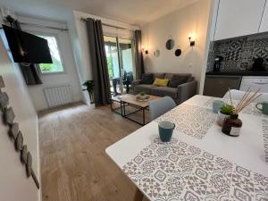 a kitchen and living room with a table and a couch at LE COSY Résidence du Golf in Deauville