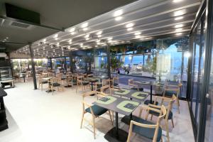 ein Restaurant mit Tischen, Stühlen und Fenstern in der Unterkunft Hotel Milenij in Makarska