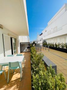 un patio con una mesa blanca y sillas en un edificio en Fantástico apartamento T2 a 2min do acesso à praia CozyIn Cabanas, en Cabanas de Tavira