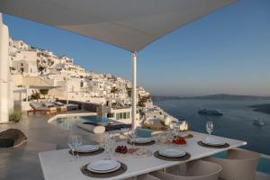a dining table with a view of the ocean at Villa Dio - An Iconic Villa Above Caldera in Firostefani