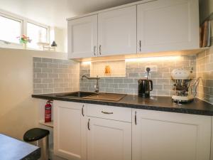 a kitchen with white cabinets and a counter top at Beehive in Matlock