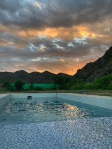 a swimming pool with a sunset in the background at Cuesta de san miguel in Chilecito