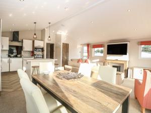 a kitchen and dining room with a wooden table and white chairs at Broadland Sands Lodge in Lowestoft