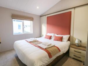a bedroom with a large white bed with a red headboard at Broadland Sands Lodge in Lowestoft