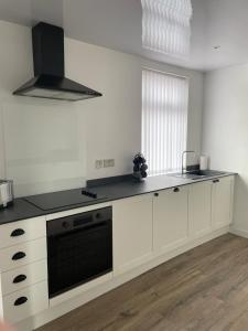 a kitchen with white cabinets and a black stove top oven at Croyden villa in Blackpool