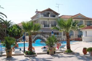 a hotel with palm trees in front of a pool at Hotel Villa Basil in Tsilivi