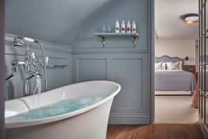 a bath tub in a bathroom with a bedroom at Moonfleet Manor - A Luxury Family Hotel in Weymouth