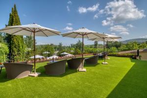 a row of lawn chairs with umbrellas on a grassy area at Hotel Costabella in Girona