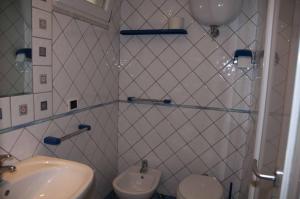 un bagno piastrellato bianco con lavandino e servizi igienici di Turistcasa - Il Pizzicato a Ponza Altre 37 foto