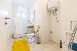 W łazience znajduje się toaleta oraz prysznic z żółtym dywanem. w obiekcie 2sis apartments w mieście Zadar