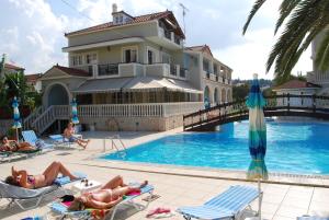a group of people laying on lawn chairs by a pool at Hotel Villa Basil in Tsilivi