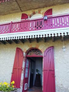 Edificio rosa con puertas rojas y balcón en L'étape du Canal - Pèlerins, Randonneurs, Vacanciers, en Condom