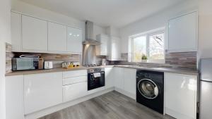 a kitchen with white cabinets and a washer and dryer at Beautiful & Spacious with 2 Free Parking Spaces - SRK Accommodation in Peterborough