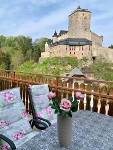 Libošovice的住宿－Hotel Podkost，花瓶,桌子上花,后面有城堡