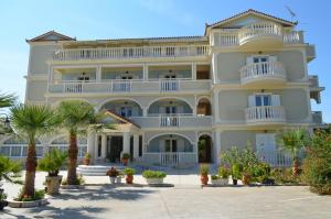 a large white building with palm trees in front of it at Hotel Villa Basil in Tsilivi