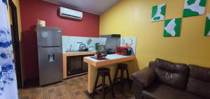 una pequeña cocina con nevera y una mesa con taburetes en Tío King Hospedaje Turístico, en Uvita