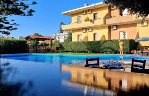a woman is standing next to a swimming pool in front of a building at Argo Apartments in Kato Daratso