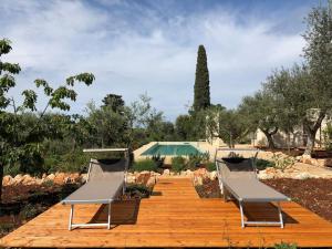 2 sillas sentadas en una pasarela de madera con piscina en Ulivo, en Monopoli